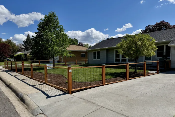 Redwood fence with black wire panels enclosing a front lawn at a street corner.
