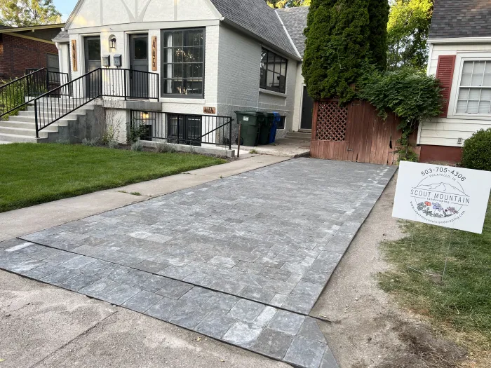 New gray paver driveway beside a white brick house, with a Scout Mountain Landscaping yard sign on the lawn.