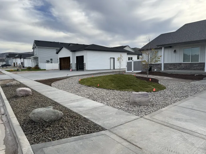 Front yard of a new home with river rock, large boulders and an oval of fresh lawn.